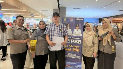 Petugas Bapenda Kota Medan menyerahkan minyak makan kepada masyarakat yang membayar PBB di Pojok Pajak.