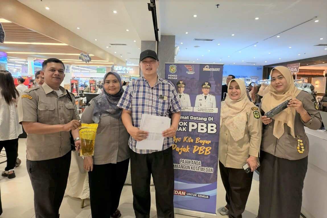 Petugas Bapenda Kota Medan menyerahkan minyak makan kepada masyarakat yang membayar PBB di Pojok Pajak.